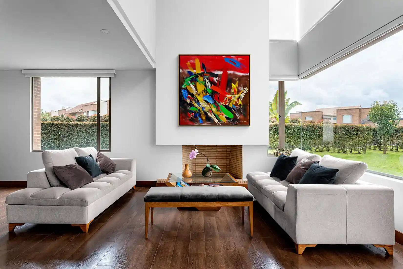 Spacious and inviting living room with expansive windows showcasing a verdant garden view, complemented by a striking abstract artwork by Armenian artist Samvel Marutyan on the wall.